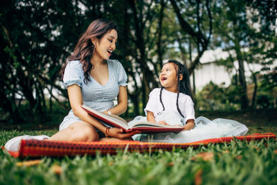 Smiling teacher and girl sitting at park