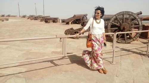 Full length of woman leaning on railing against cannons