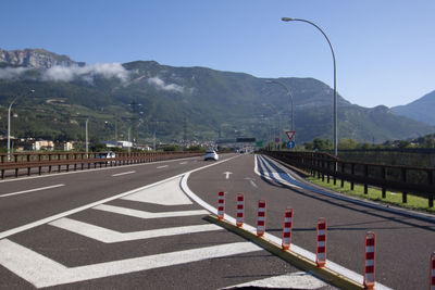 Country road leading towards mountains against clear sky