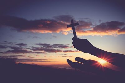 Low angle view of silhouette woman holding hands against sky during sunset