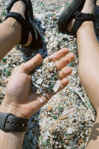 Low section of person holding pebbles on rock