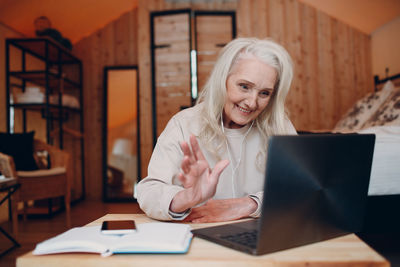 Woman using phone while sitting on table