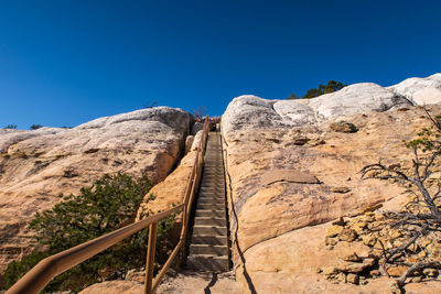 Landscape looking up a massive stone wall and staircase at el morro national monument in new mexico