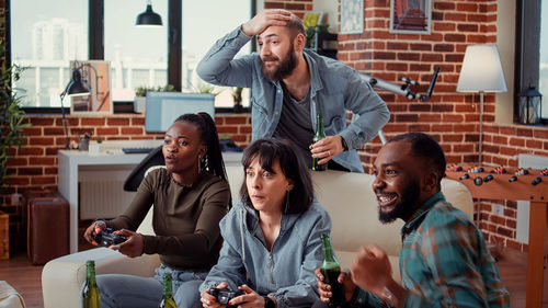 Portrait of smiling friends using smart phone while sitting at home