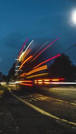 Light trails in city against sky at night