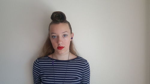 Portrait of a young woman against wall