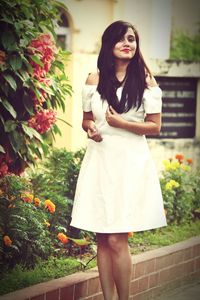 Portrait of a smiling young woman standing against white wall