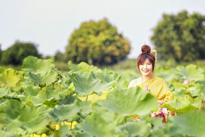 Portrait of young woman wearing traditional clothing standing amidst plants