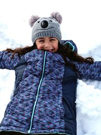 High angle portrait of happy girl making snow angle on field