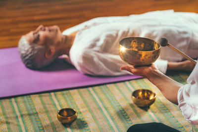 Cropped hands of woman playing singing bowl for customer in spa