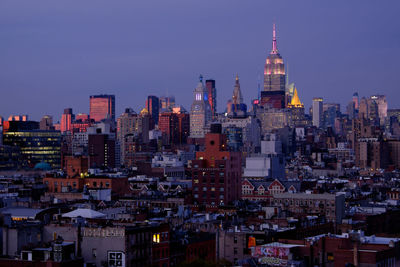Illuminated empire state building in city against sky at dusk