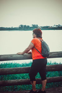 Rear view of woman standing by railing against sky