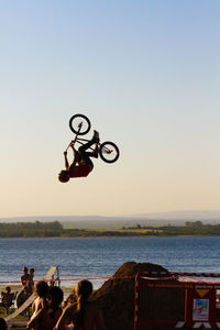 People jumping by sea against clear sky