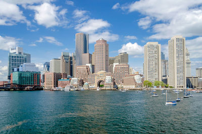 Sea by modern buildings against sky in city