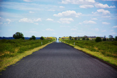 Road amidst field against sky