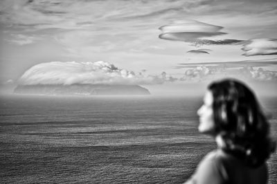 Woman flying over sea against sky