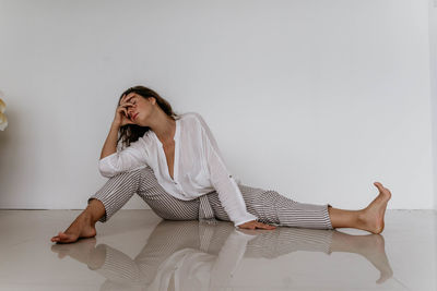 Low section of woman sitting on bed at home
