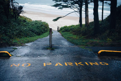 Road sign by trees against sky