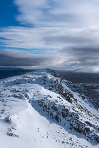 Scenic view of snowcapped mountains against cloudy sky