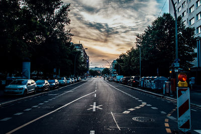 Cars on road against cloudy sky