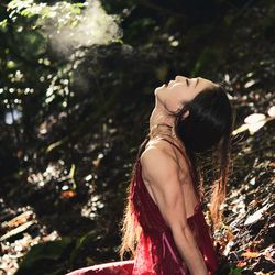 Midsection of woman with arms raised in forest