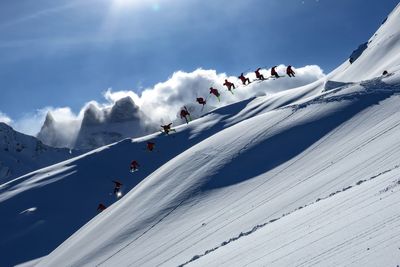 Multiple image of man skiing on snowcapped mountain against sky