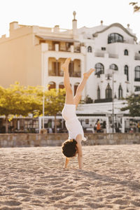 Full length of girl performing handstand on beach