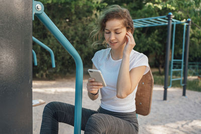 Full length of woman using mobile phone outdoors