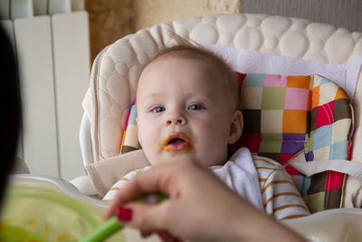 Cropped hand of woman by cute baby boy at home