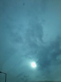 Low angle view of sun shining through clouds