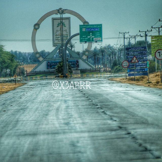 built structure, transportation, the way forward, clear sky, architecture, text, graffiti, communication, building exterior, street, road, western script, day, outdoors, tree, sky, sign, diminishing perspective, empty, road sign