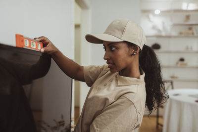 Female technician examining level on television set at home