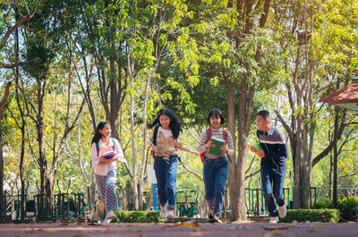 Full length of children running on road against trees in park