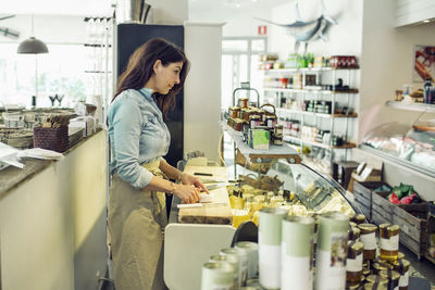 Side view of mature saleswoman at supermarket counter