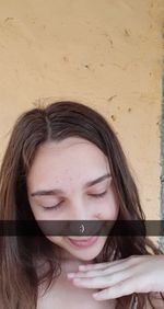 Close-up portrait of young woman drinking against wall