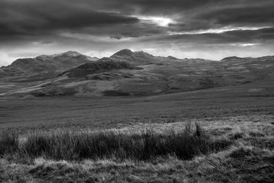 Scenic view of landscape and mountains against cloudy sky