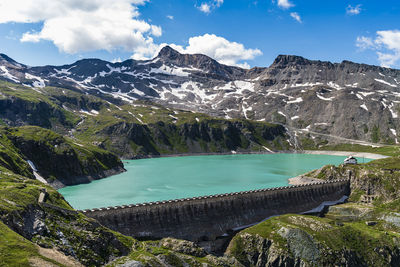 Panorama of embankment in mountains with snow peaks, and beautiful sky.