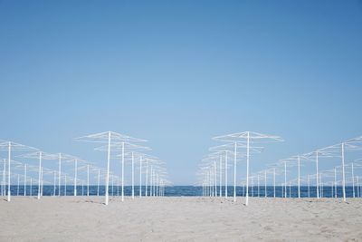 Empty parasols on beach against clear blue sky