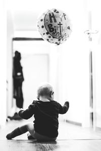 Rear view of boy sitting on floor at home