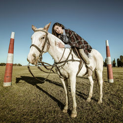 Portrait of woman leaning on horse over field