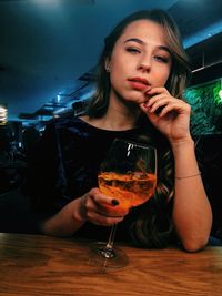 Portrait of young woman having drink at table in restaurant