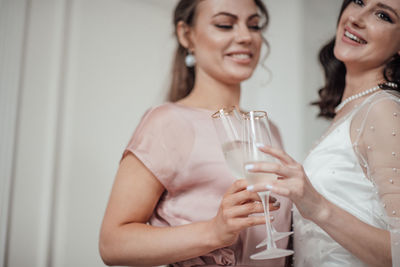 Bridesmaid and bride holding champagne flute