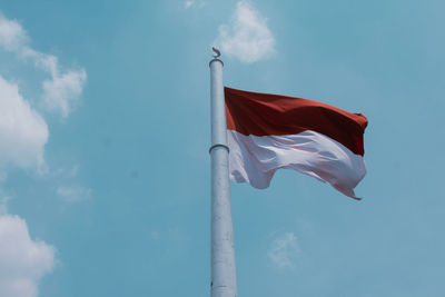 Low angle view of flag against blue sky