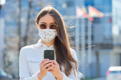 Woman wearing mask taking selfie on street