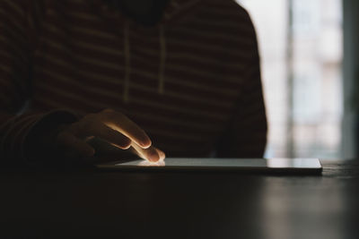 Midsection of man using smart phone on table