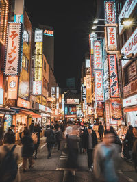 People walking on illuminated street in city at night