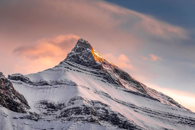 Scenic view of snowcapped mountains against cloudy sky during sunset