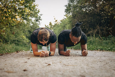 Determined man and woman doing plank on footpath