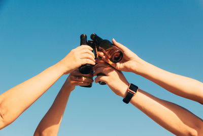 Closeup shot of bottles lifted high on blue sky background