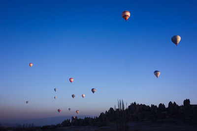 Low angle view of hot air balloon flying against clear blue sky during sunset